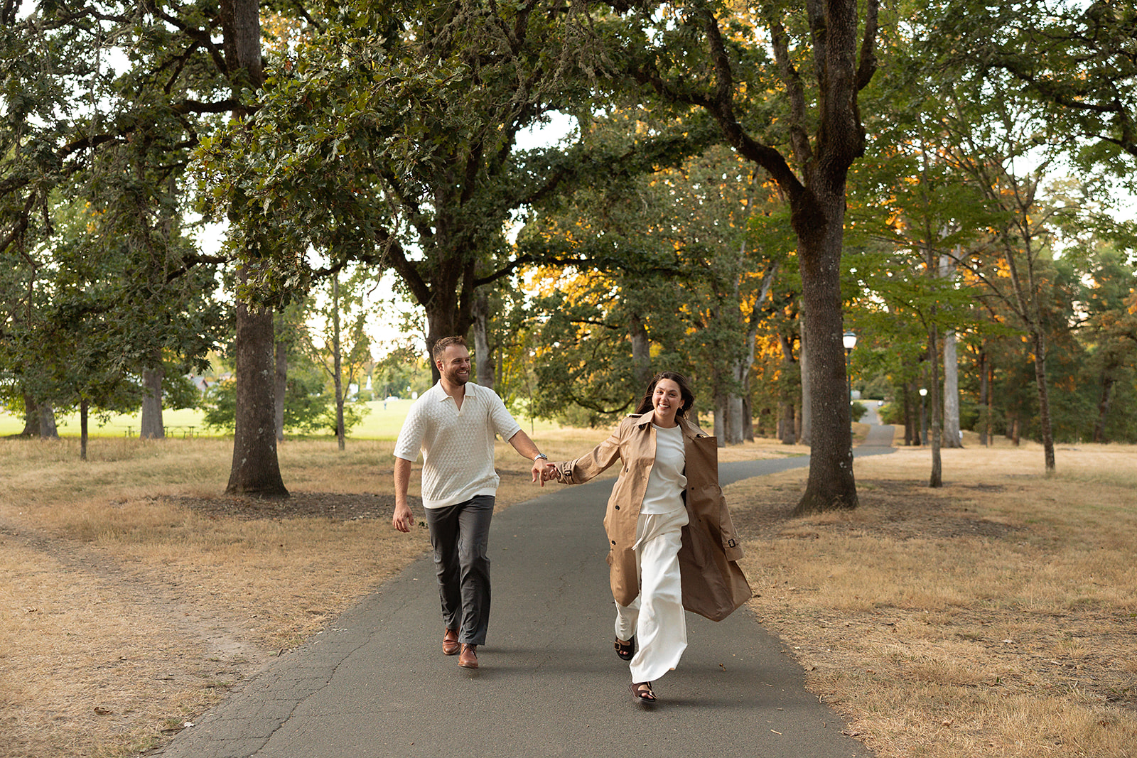 A fall engagement session of a couple running through a park at the Deepwood Museum and Gardens